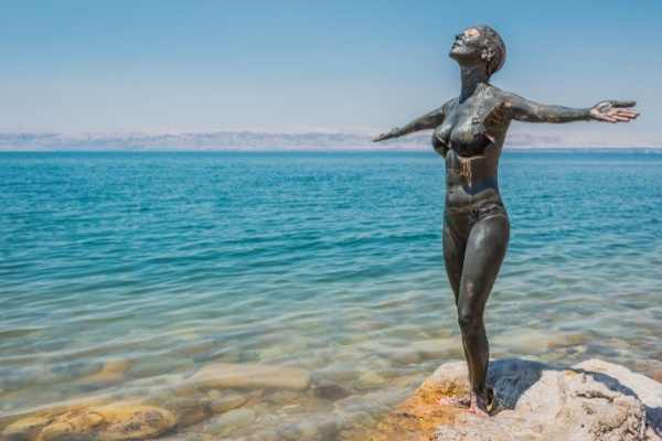 Dead Sea Floating Woman standing in Dead Sea covering in healing mud