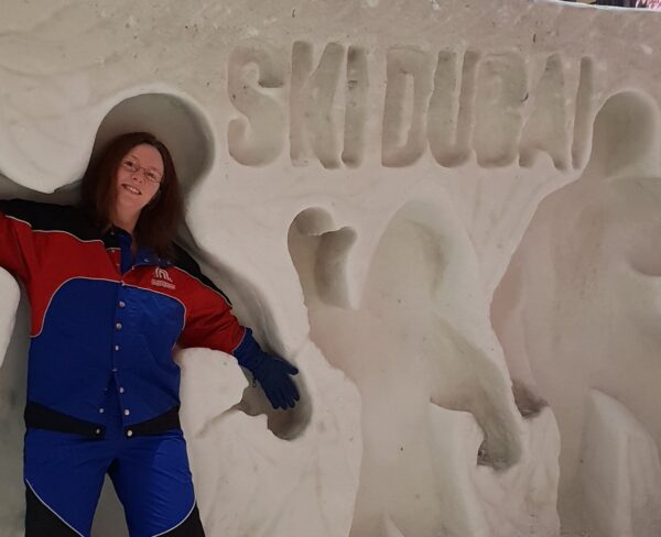Woman dressed in Ski Dubai snow gear playing in human sized shapes at the resort. 