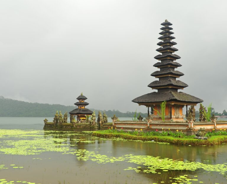 Traditional Balinese Hindu temple, Pura Ulun Danu Bratan, on a cloudy day with the lake's surface covered in water lilies.